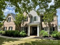 Charming brick home boasts manicured landscaping, a welcoming front porch, and mature trees at 1210 Langdon Terrace Dr, Indian Trail, NC 28079