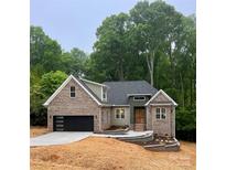 Beautifully landscaped brick home featuring a modern garage door and elegant front entrance at 2108 Lakeview Cir, Matthews, NC 28105