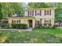 Charming two-story home with yellow siding, red shutters, and a brick entryway at 6807 Woodfield Dr, Charlotte, NC 28215