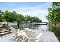 Relaxing dock with comfortable Adirondack chairs overlooking the serene waterfront with boats and lush greenery, perfect for lakeside living at 7471 Barfield Ln, Denver, NC 28037