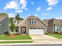 Charming stone-and-brick home featuring a well-manicured lawn, a two-car garage, and an inviting arched entrance at 3199 Windhaven Ln, Tega Cay, SC 29708