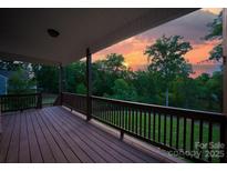 Inviting covered back deck with wood flooring and picturesque sunset views overlooking manicured backyard at 444 Snapdragon Dr, Clover, SC 29710