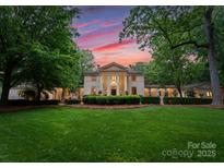 Stately home with manicured lawn, mature trees, and impressive architectural details at sunset at 5030 Hardison Rd, Charlotte, NC 28226