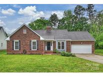 Charming brick home with a manicured lawn, mature trees and an attached two car garage at 616 Trailing Rock Dr, Charlotte, NC 28214