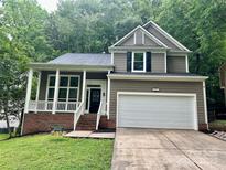 Charming two-story home with a white garage door, covered porch, and well-manicured lawn at 7401 Kinsmore Ln, Charlotte, NC 28269