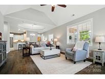 Bright living room features hardwood floors, a tray ceiling, and a view into the kitchen at 8473 Bing Cherry Dr, Denver, NC 28037