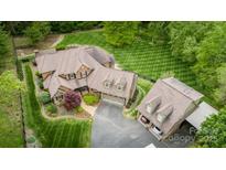Sprawling estate with manicured lawn, featuring a brick home and detached garage, surrounded by mature trees at 4600 Spicewood Dr, Charlotte, NC 28227