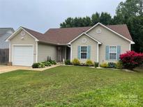 Inviting one-story home featuring a lush front yard with a garage and pleasing exterior siding at 5804 Crosswinds Ct, Indian Trail, NC 28079