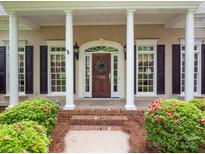 Inviting front porch with stately columns, decorative wreath, and blossoming shrubs at 7716 Seton House Ln, Charlotte, NC 28277