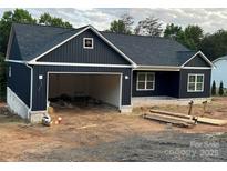 New construction home features a dark blue exterior, white brick base, a garage, and a modern roof line at 85 Cornerstone Dr, Taylorsville, NC 28681