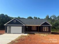 Charming home featuring a modern garage, dark siding, and a welcoming front porch at 85 Cornerstone Dr, Taylorsville, NC 28681