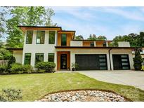Modern two-story home with a lush green lawn and a three car garage at 9305 Valley Rd, Charlotte, NC 28270