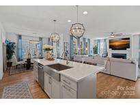 Open-concept kitchen with stainless steel appliances, quartz countertops, and pendant lighting flowing into the living room at 14004 Fiery Mist Way, Huntersville, NC 28078