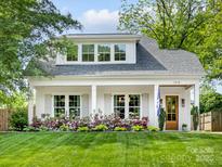 Charming home featuring a manicured lawn, a light gray roof, white trim and a welcoming front porch at 1614 Brook Rd, Charlotte, NC 28205