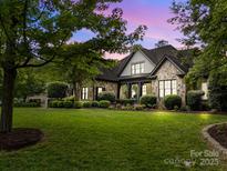 Beautiful stone home with a well-manicured lawn and lush landscaping showcasing its curb appeal at 21305 Sandy Cove Rd, Cornelius, NC 28031