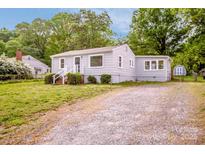 Charming single-story home with light gray siding and gravel driveway surrounded by lush greenery at 444 Oakwood Ave, Mooresville, NC 28115