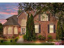 Beautiful brick home featuring a manicured lawn, mature trees, and elegant architectural details at twilight at 4563 Osprey Run Ct, Denver, NC 28037