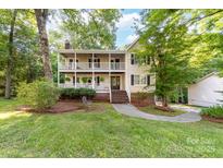 Charming two-story home featuring a double porch and inviting curb appeal surrounded by mature trees at 552 Blue Rock Dr, Charlotte, NC 28213