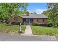 Charming brick home featuring a well-manicured lawn and inviting front porch, perfect for relaxed outdoor living at 7221 Leaves Ln, Charlotte, NC 28213