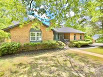 Charming brick home with well-maintained landscaping, lush greenery, and inviting facade at 7221 Leaves Ln, Charlotte, NC 28213