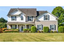 Charming two-story home with well-manicured lawn and landscaping and a mix of siding and architectural details at 7325 Forrest Rader Dr, Mint Hill, NC 28227