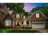 Charming two-story brick home featuring a welcoming front porch with white columns and manicured landscaping at 7811 Compton Ct, Charlotte, NC 28270