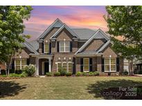 Beautiful two-story brick home with a manicured lawn, black shutters, and mature trees enhancing its curb appeal at 10202 Alouette Dr, Waxhaw, NC 28173