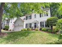Charming two-story white home with black shutters, attached garage and manicured lawn and landscape at 12328 Chickasaw Dr, Huntersville, NC 28078