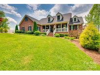 Beautiful brick home featuring a welcoming front porch and lush, green landscaping at 181 Edgewater Rd, Hickory, NC 28601
