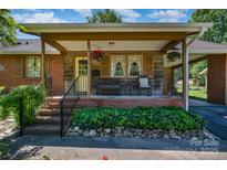 Charming brick home featuring a cozy covered front porch with inviting seating and hanging flower baskets at 3624 Delgany Dr, Charlotte, NC 28215