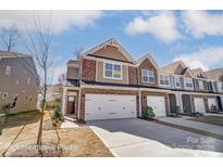 New two-story townhome featuring brick accents, white garage door, and a manicured lawn at 4254 Black Ct # 231, Harrisburg, NC 28075