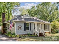 Charming single-story home featuring gray siding, black shutters, an American flag, and manicured landscaping at 6412 Old Meadow Rd # 69, Charlotte, NC 28227