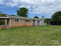 Charming brick ranch home featuring a stone chimney and a large grassy yard at 975 22Nd Street Ne Pl, Hickory, NC 28601