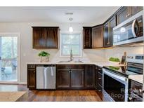 Well-lit kitchen with stainless steel appliances, dark wood cabinets, and stylish countertops at 2835 24Th Street Ne Dr, Hickory, NC 28601