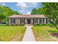 Charming brick home with a lush green lawn and manicured landscaping in front at 5522 Sharon Rd, Charlotte, NC 28210