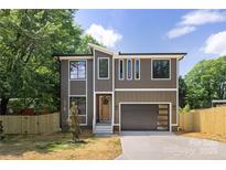Two-story home featuring a modern design, large windows, stylish wood door, and an attached garage at 816 Tennyson Dr, Charlotte, NC 28208