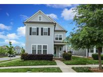 Charming two-story home with light-blue siding, black shutters, manicured landscaping, and inviting front porch at 13624 Jacks Ln, Pineville, NC 28134