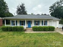 Charming home featuring a covered front porch, bright blue door and shutters, and manicured landscaping at 1401 Thompson Ave, Charlotte, NC 28216