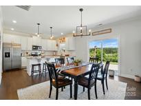 Bright dining area with wood floors, stylish lighting and an adjacent modern kitchen with white cabinetry at 4321 Hornyak Dr, Monroe, NC 28110