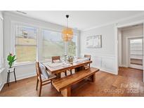 Bright dining area features a wooden table, bench, chairs, and large windows overlooking the green landscape at 528 Rock Skip Way, Fort Mill, SC 29708