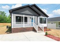 Charming home with a covered porch, brick foundation, white railings, and a bright blue front door at 640 Central Nw Dr, Concord, NC 28027