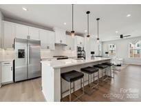 Modern kitchen boasts white cabinets, stainless steel appliances, and a large island with seating at 9823 Oaklawn Nw Blvd, Huntersville, NC 28078