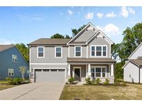 Charming two-story home with a gray exterior, covered porch, and well-maintained landscaping at 1308 Stone Marker Dr, Monroe, NC 28112