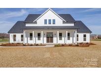 Stunning white farmhouse featuring a charming front porch with classic columns and a double door entrance at 1706 Ruben Rd, Monroe, NC 28112