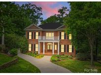 Elegant two-story brick home featuring white columns, balcony, dark shutters and a beautifully landscaped front yard at 1806 Asbury Hall Ct, Charlotte, NC 28209