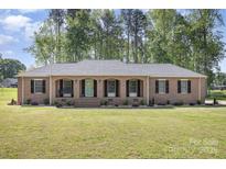 Charming single-story brick home featuring arched entryway, manicured lawn and mature trees at 205 Timberfield Trl, China Grove, NC 28023