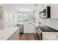 Bright white kitchen with stainless steel appliances, stone countertops, and island at 2111 Isom St, Charlotte, NC 28208