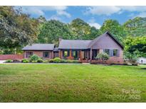 Charming brick home featuring a well-manicured lawn and inviting front porch with wood columns at 2202 Bearskin Ln, Monroe, NC 28110