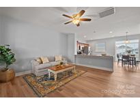 Open-concept living area with wood floors, a neutral sofa, access to the kitchen, and plenty of natural light at 233 E Waterlynn Rd # B, Mooresville, NC 28117