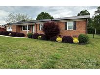 Charming brick home with a black metal roof and well-manicured landscaping at 396 Pitts School Nw Rd, Concord, NC 28027